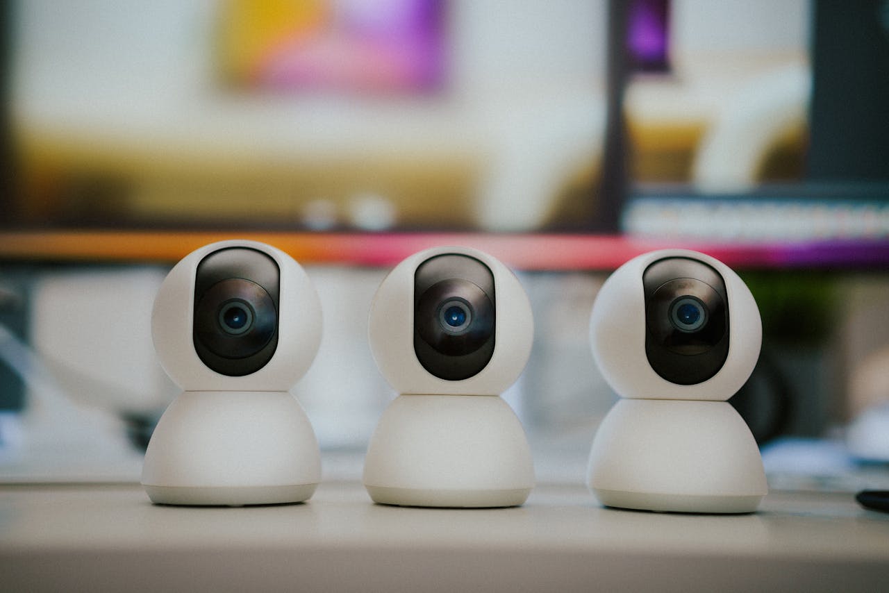 Three modern smart home security cameras placed on a table indoors with a blurry background.